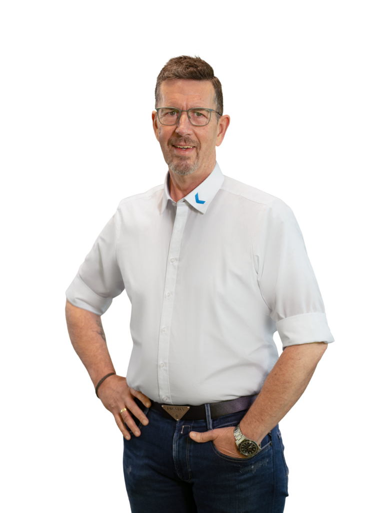 Mann in weißem Hemd und Jeans mit Brille, lächelnd.