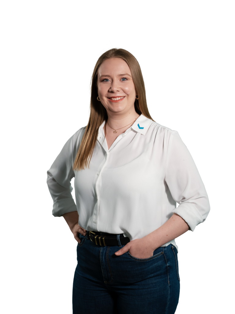 Frau in weißer Bluse und blauer Jeans lächelt in die Kamera.