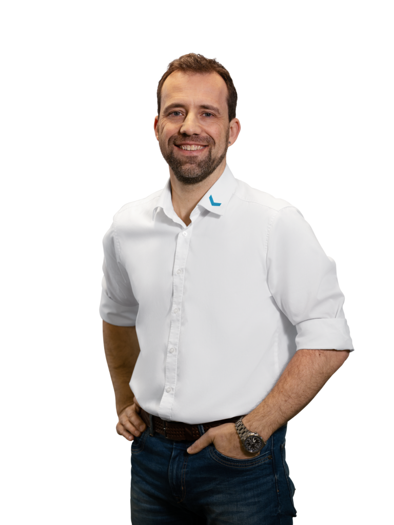 Mann in weißem Hemd und Jeans lächelt in die Kamera