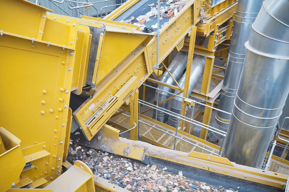 Instalação de reciclagem amarela para resíduos mistos da construção, equipada com uma correia transportadora.