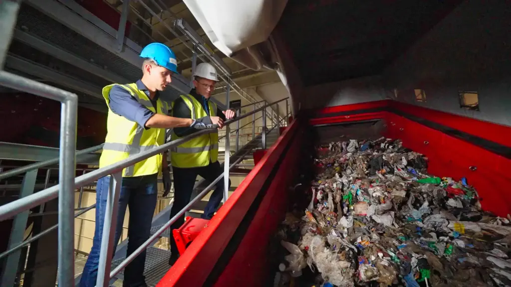 Dois especialistas em reciclagem observam uma máquina de crivagem SPALECK numa grande instalação de reciclagem de resíduos domésticos.