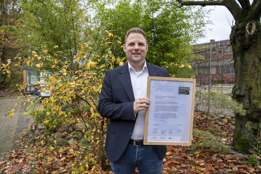 Homem segura um certificado ao ar livre, simbolizando a sustentabilidade na SPALECK.