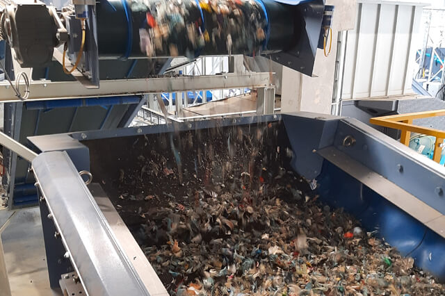 O material cai de uma correia transportadora para um crivo de eixo tensado.