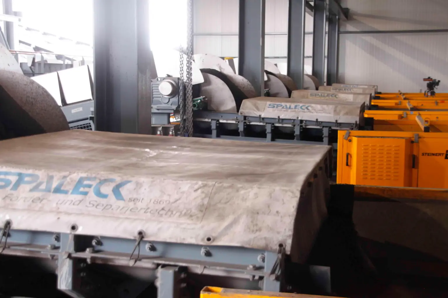 Canais transportadores oscilantes SPALECK ActiveCLEAN em utilização no tratamento de escórias; neste contexto, permitem um fornecimento sem aderências aos equipamentos de triagem