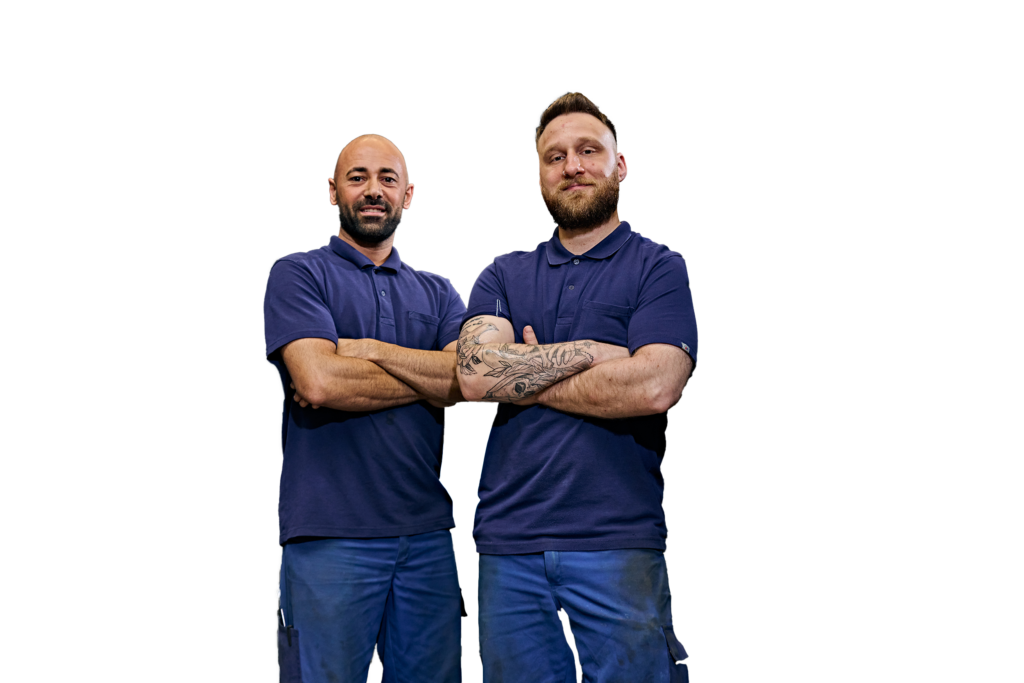 Dois homens vestidos com roupa de trabalho estão lado a lado, com ar de segurança.