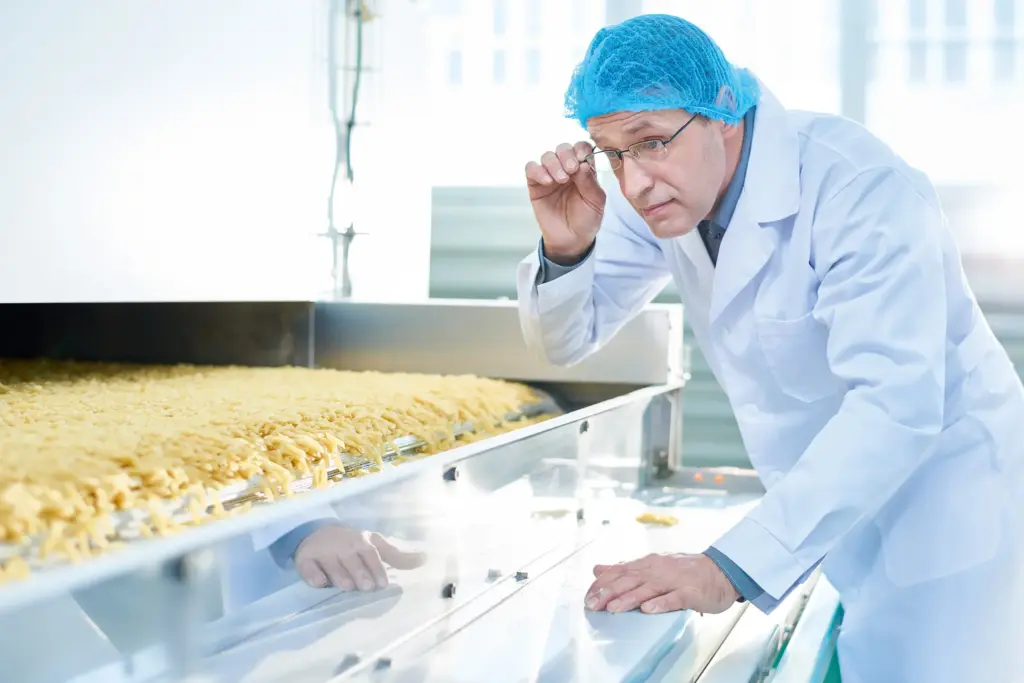 Um homem com equipamento de proteção inspeciona a produção alimentar.