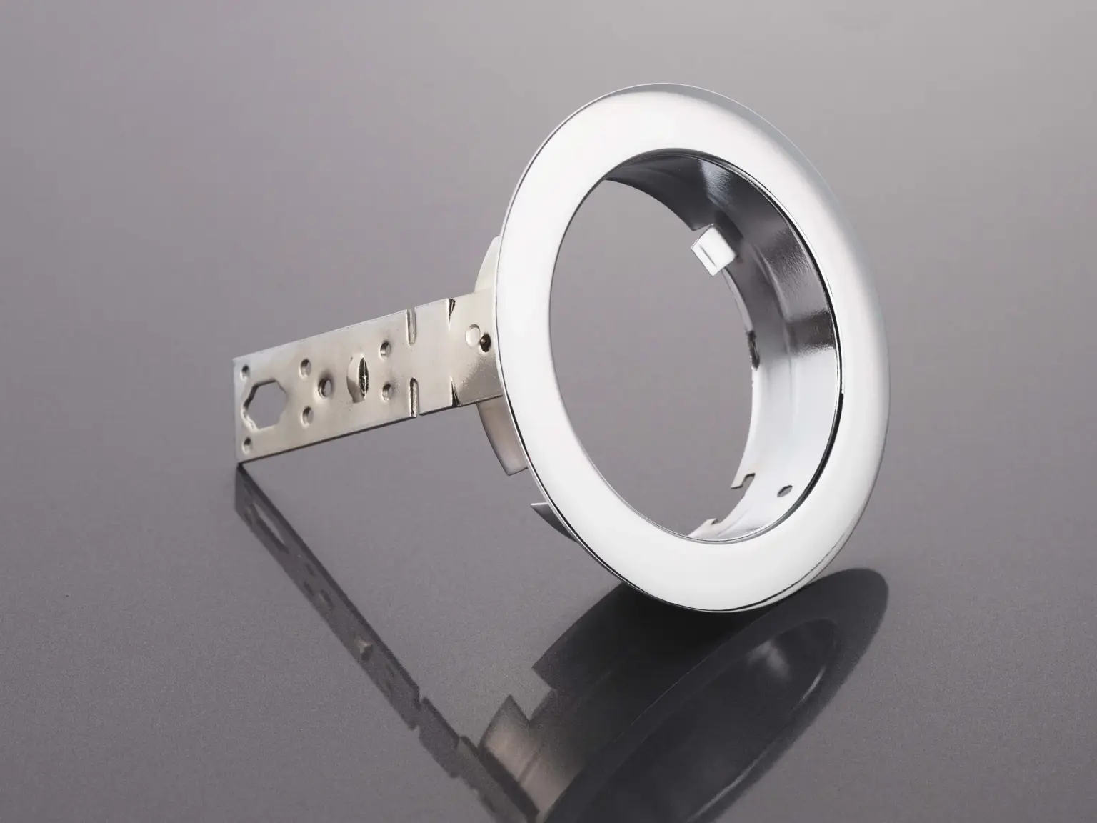 Peça metálica com superfície tratada sobre um fundo refletor.