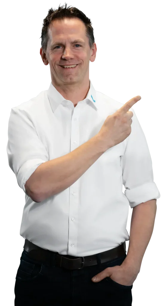 Um homem de camisa branca aponta para o lado, sorrindo.