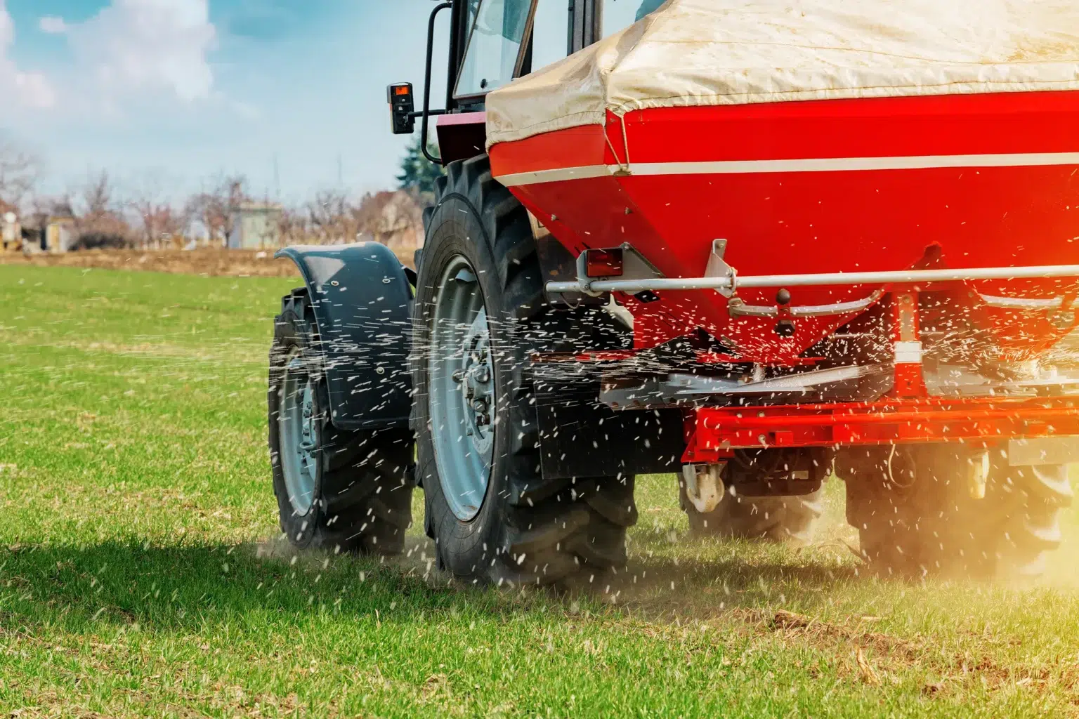 Um trator espalha fertilizante num campo. Isto demonstra a quantidade de fertilizantes necessária a nível mundial.
