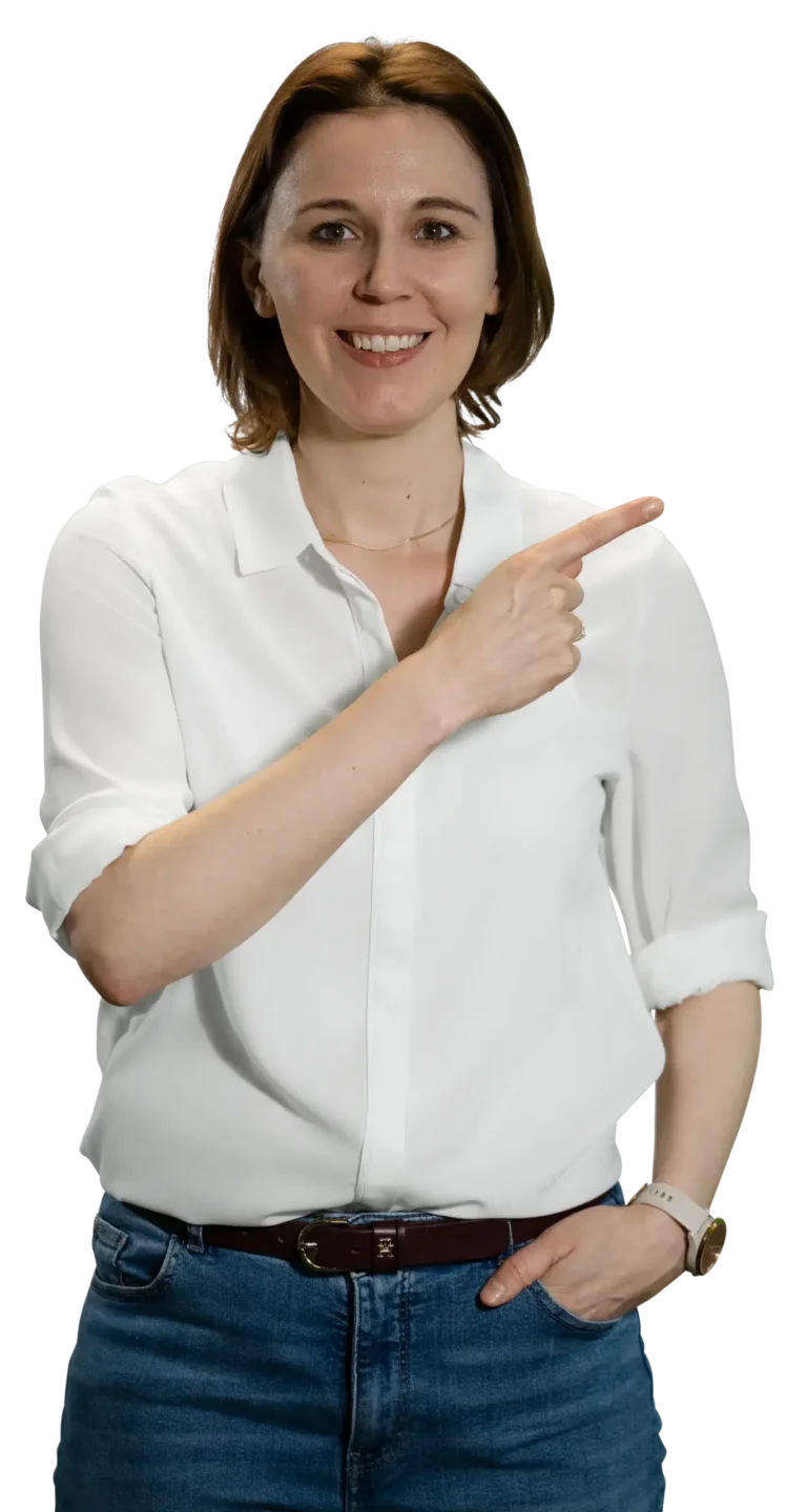 Uma mulher de camisa branca e calças de ganga aponta para o lado, sorrindo.
