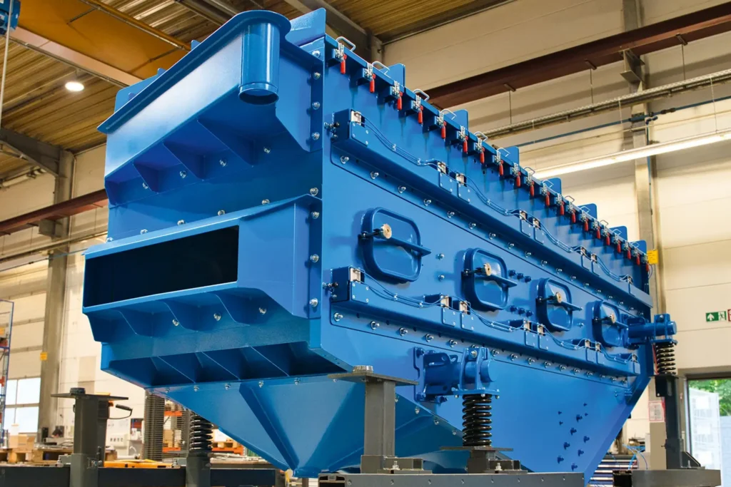 Grande máquina metálica azul num pavilhão industrial, adequada para o TRATAMENTO DE SUPERFÍCIES.