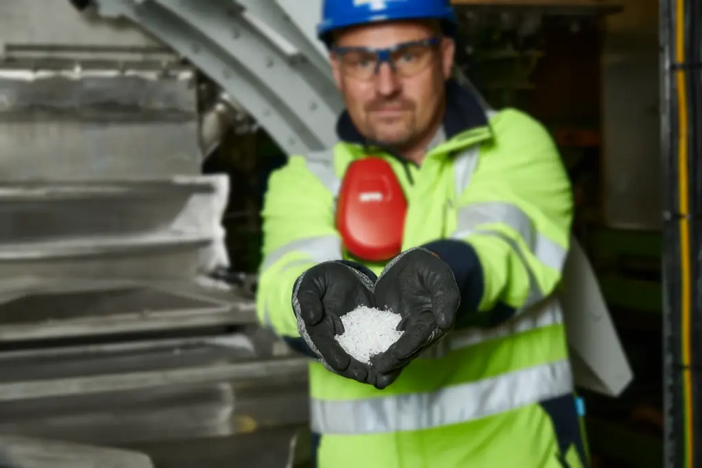 Um funcionário da linha de produção de um fabricante de granulado de plástico mostra à câmara o granulado recém-produzido e peneirado para controlo de qualidade