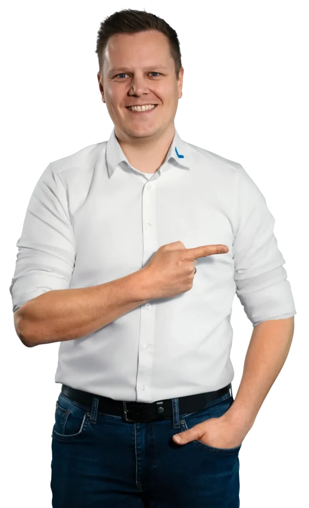 Um homem de camisa branca aponta para o lado, sorrindo.