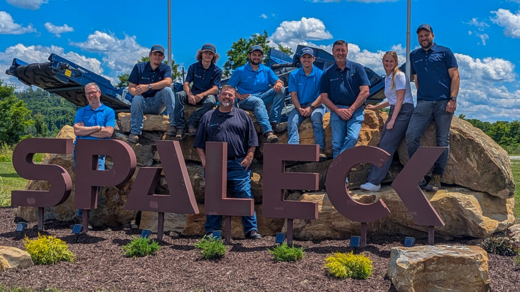 Fotografia de grupo da Spaleck USA junto ao logótipo da Spaleck em Charleroi, por ocasião da inauguração das instalações, sob um céu azul