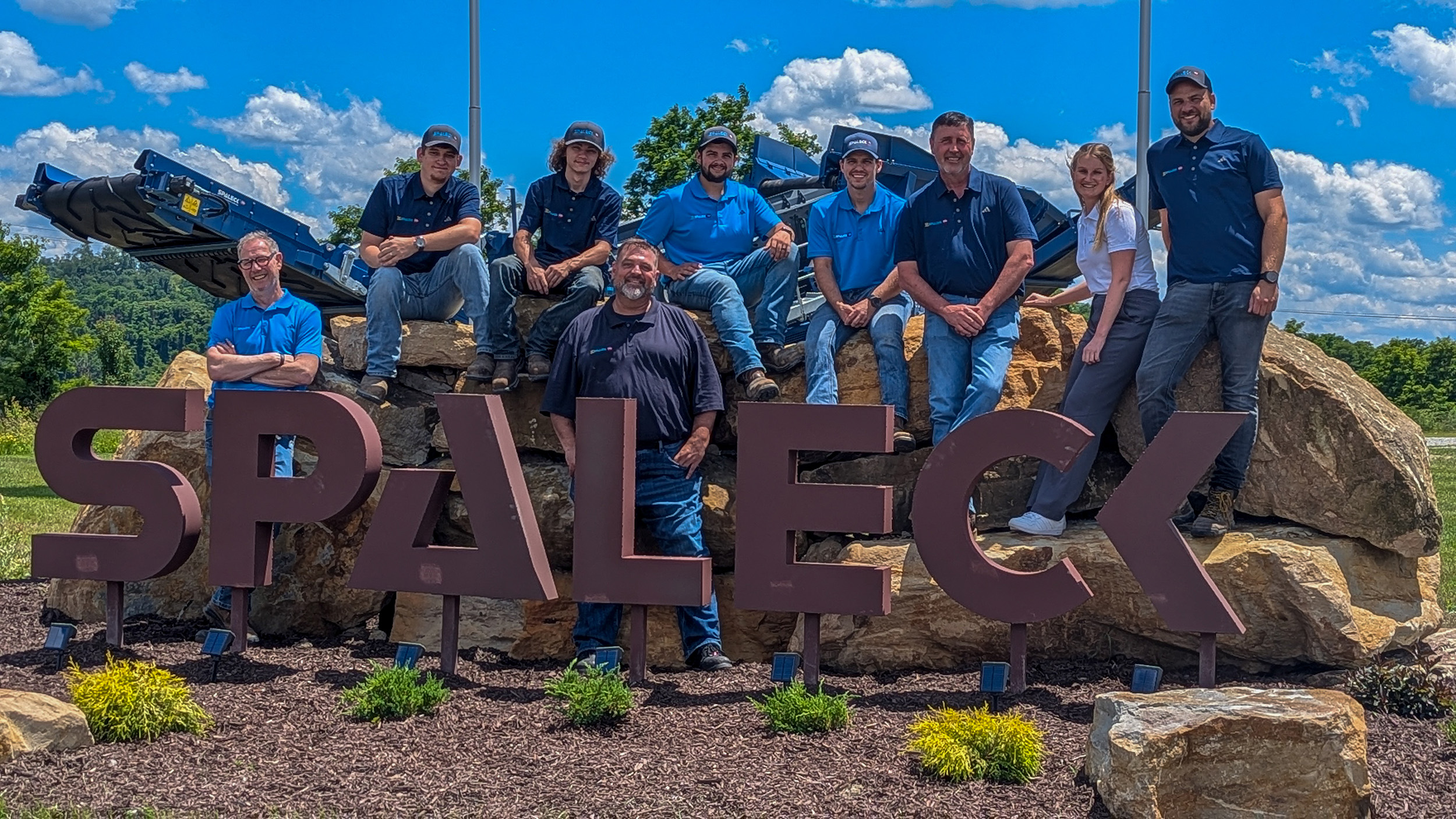 Fotografia de grupo da Spaleck USA junto ao logótipo da Spaleck em Charleroi, por ocasião da inauguração das instalações, sob um céu azul